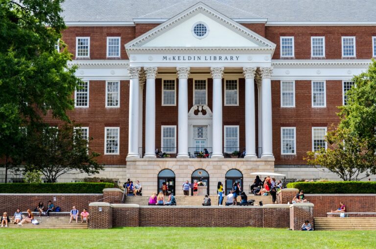Photo of a university library that has been designed in a neoclassical style—a brick facade with a white portico supported by corinthian columns.