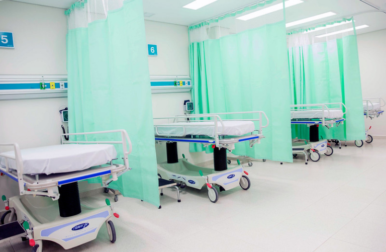 Hospital beds separated by green curtains