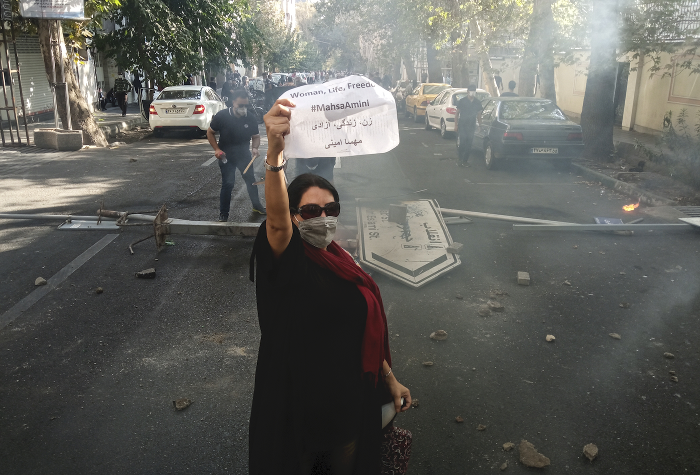 A woman protesting on the streets of Iran holds up a sign that says "Women, Life, Freedom."