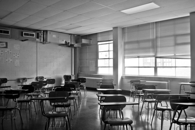 Black and white image of a classroom with empty desks.