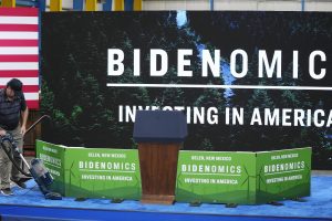 A worker vacuums the carpeting on the stage prior to President Joe Biden speaking about the economy at Arcosa Wind Towers factory Wednesday, Aug. 9, 2023, in Belen, N.M. (AP Photo/Ross D. Franklin)