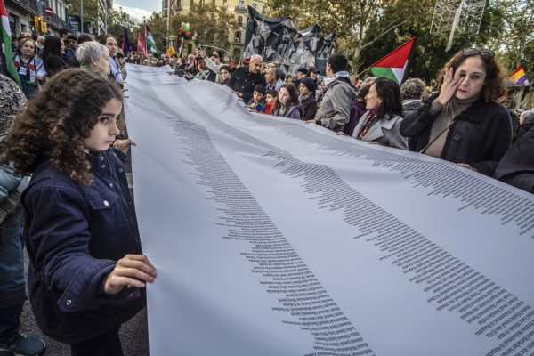 A woman is seen crying in front of her daughter, both carrying a large list of names of those killed by bombs during the demonstration. Some 7,500 people demonstrated in the center of Barcelona to demonstrate their support and solidarity with the Palestinian people, rejecting the genocide by the Israeli armed forces. The demonstration ended with the temporary occupation of the Francia station where the regional police intervened to evict it. (Photo by Paco Freire / SOPA Images/Sipa USA)(Sipa via AP Images)