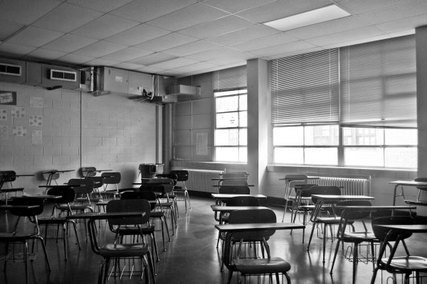 Black and white image of a classroom with empty desks.