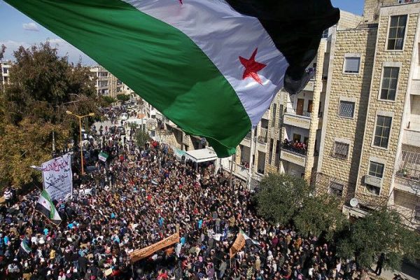 Syria independence flag flies over a large pathering of protesters in Idlib.