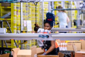 A woman works at a distrubiton station at the 855,000-square-foot Amazon fulfillment center in Staten Island, one of the five boroughs of New York City, on February 5, 2019. - Inside a huge warehouse on Staten Island thousands of robots are busy distributing thousands of items sold by the giant of online sales, Amazon. (Photo by Johannes EISELE / AFP)        (Photo credit should read JOHANNES EISELE/AFP via Getty Images)