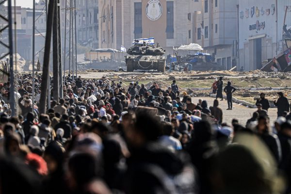 An Israeli tank and other military vehicles guard a position as Palestinians flee Khan Yunis in the southern Gaza Strip  on January 26, 2024, amid ongoing battles between Israel and the Palestinian militant group Hamas. (Photo by Mahmud Hams / AFP)