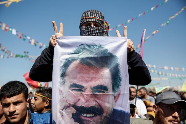 DIYARBAKIR, TURKEY - MARCH 21: A Kurdish man flashes V-sign as he holds a flag with a picture of the jailed PKK leader Abdullah Ocalan during Newroz celebrations, on March 21, 2015 in Diyarbakir, Turkey. Thousands of Kurds gather for the Newroz spring festival in Diyarbakir in southeast Turkey under tight security after months of fighting between security forces and Kurdish separatists, and a series of bombings in Istanbul and Ankara. (Photo by Ulas Tosun/Getty Images)