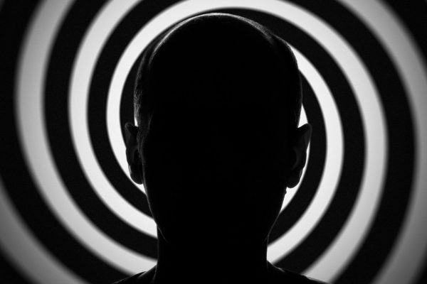 Head and shoulders man’s silhouette in front of a spiral pattern. Conceptual image about modern people’s confusion, and mind control.